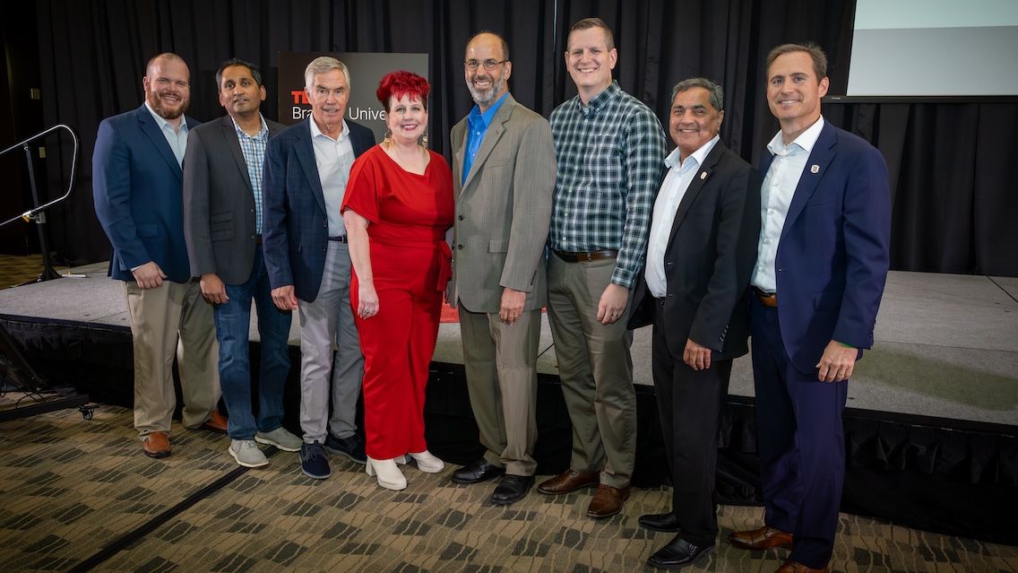 Speakers and organizers for the TEDx Bradley University event pose in front of the stage