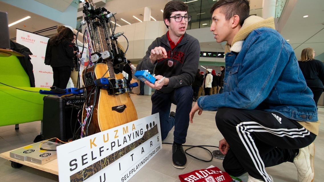 Michael Kuzma, creator of a self-playing guitar, showcases his invention inside Bradley University's Business and Engineering Convergence Center.