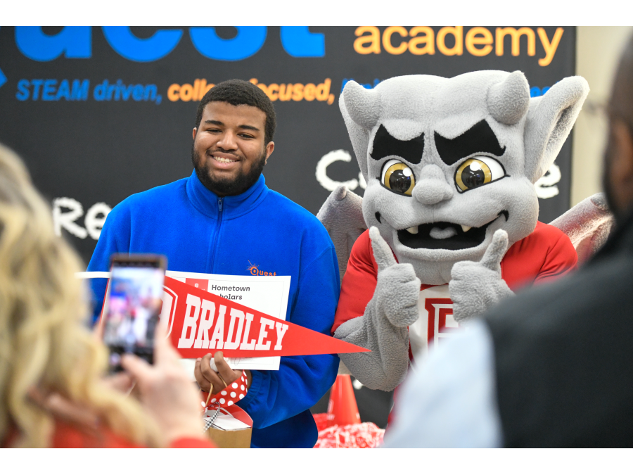 Quest Charter Academy senior Christopher Hudson Jr. (entrepreneurship) received his Hometown Scholar award from Bradley University in a surprise presentation at Quest Charter Academy. He is joined by the Bradley mascot Kaboom!