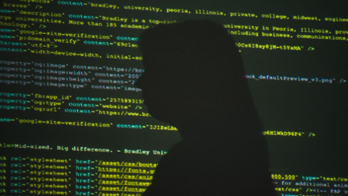 Silhouette photo with computer code in the background.